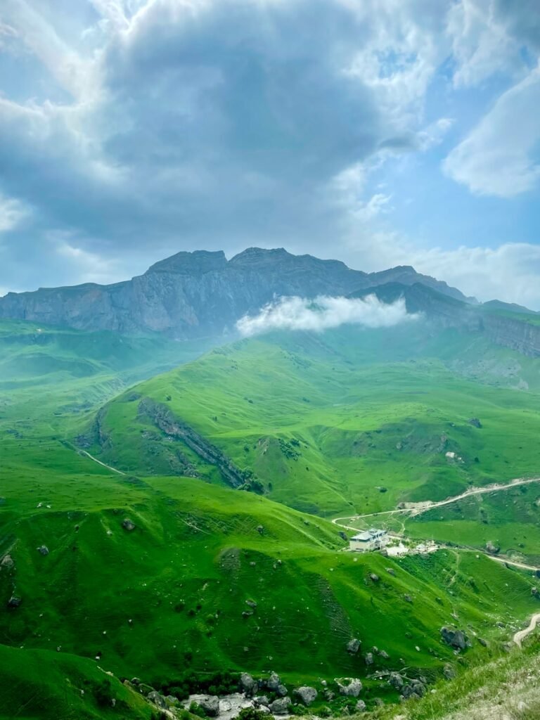 gündüz vakti beyaz bulutların altında yeşil dağlar